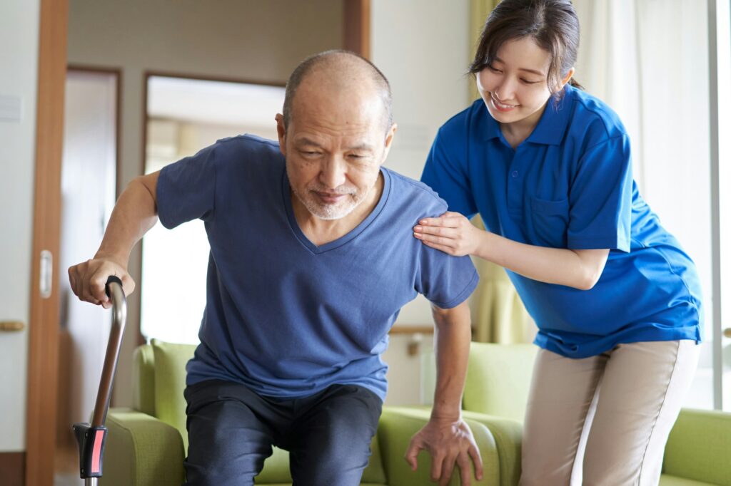 A caregiver who assists the elderly with a cane